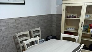 Ein Esstisch mit vier Stühlen, einer gefliesten Spritzschutzwand und einem Schrank mit Geschirr.
