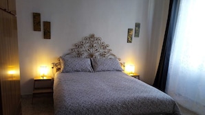 Un dormitorio con cama, dos lámparas de noche y decoración en la pared.