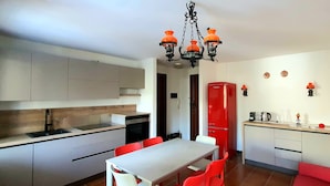A compact kitchen with a dining area, a red refrigerator, and a chandelier. - Mont Blanc Apt- Bluchalet  (Courmayeur)