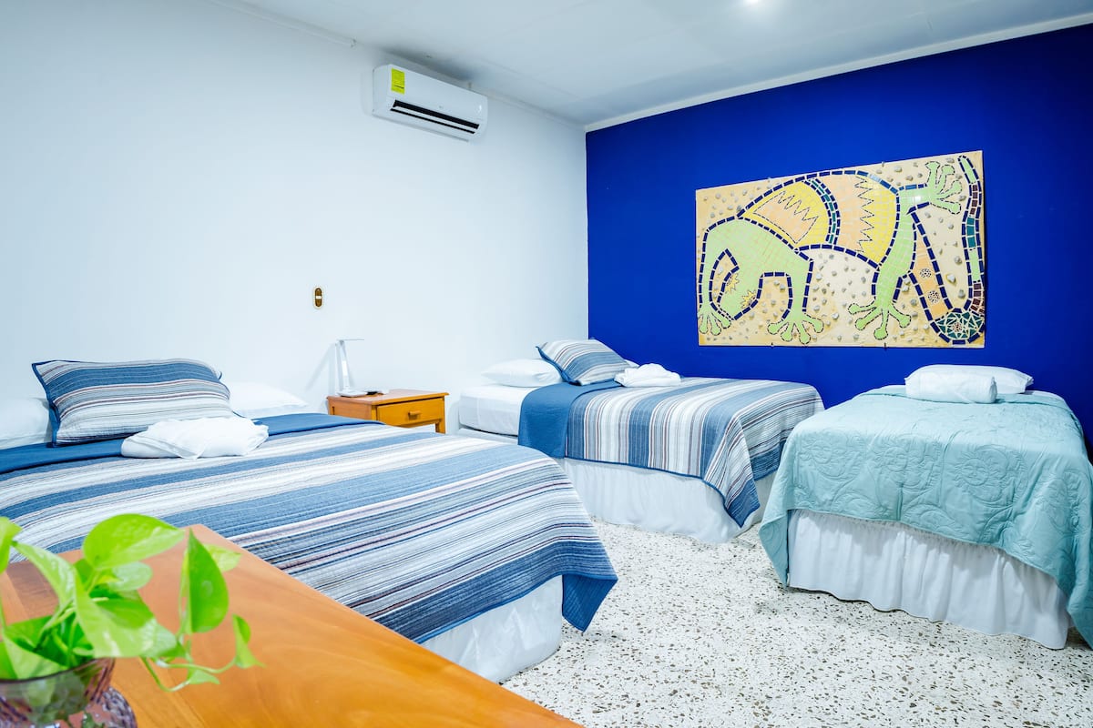 Une chambre d’hôtel avec deux lits, une table en bois et un climatiseur fixé au mur.