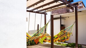 Een overdekte buitenruimte met een hangmat en een pergola.