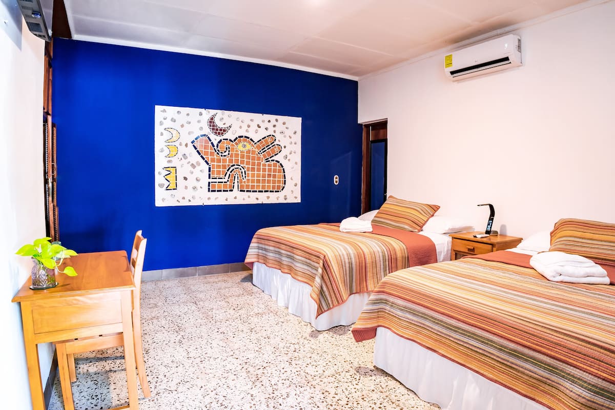 Une chambre avec deux lits, un bureau et une fresque murale.