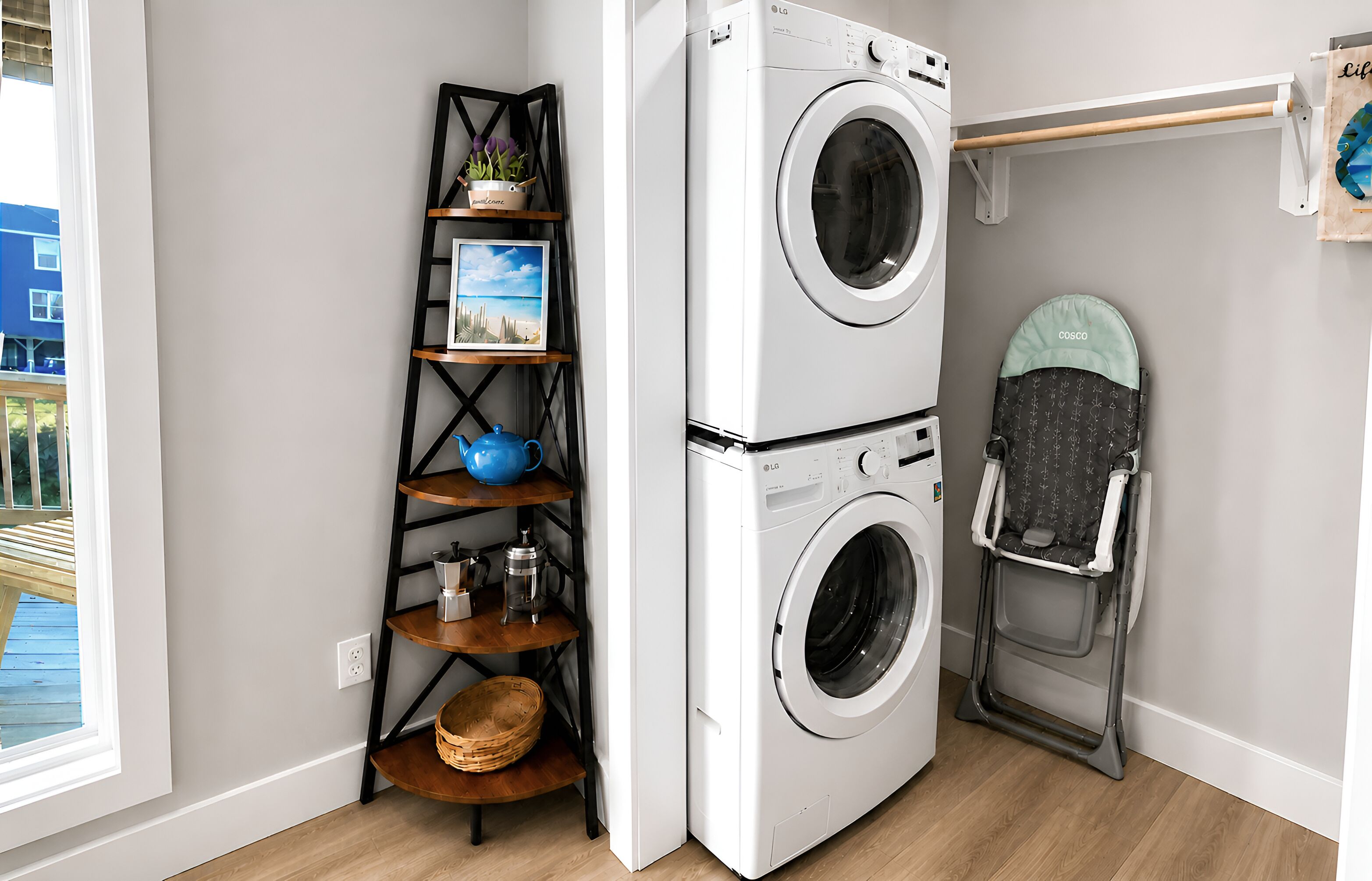 A laundry area with a stacked washer and dryer, a shelf with various items, and a stroller.