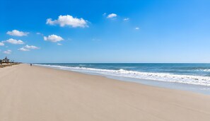Une vaste plage, un ciel dégagé et une mer calme.