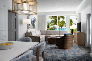 A modern living room with a sofa, a dining table, and a TV. There is a view of palm trees and the ocean through large windows. - Marriott Ocean Pointe, Oceanside, Kitchen, Access to Resort Amenities (Palm Beach Shores)
