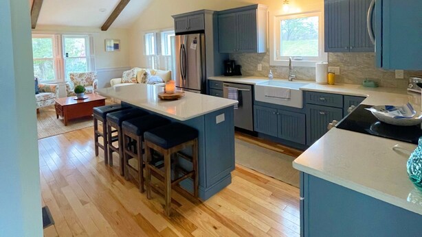 Una cocina amplia con vigas de madera, una isla grande y armarios azules.