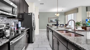 A modern kitchen with dark cabinetry, stainless steel appliances, and a granite countertop. - Beautiful Town Home with Splash Pool-4804CS (Kissimmee)