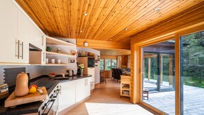 Een moderne keuken met een houten plafond en grote schuifdeuren die uitkomen op een terras.