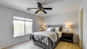 A bedroom with a bed, nightstands, a ceiling fan, and a window. - Putting Green, Pool & Spa: Home in Queen Creek! (Queen Creek)