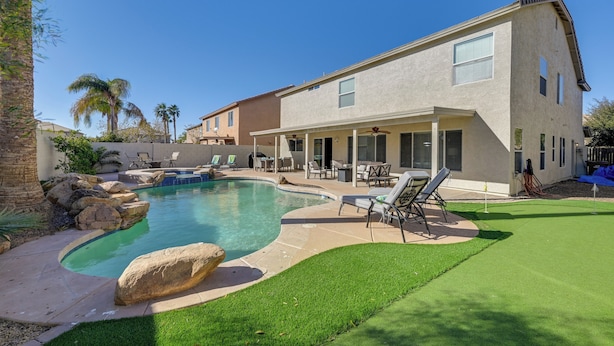 A two-story house with a swimming pool, patio furniture, and a well-maintained lawn. - Putting Green, Pool & Spa: Home in Queen Creek! (Queen Creek)