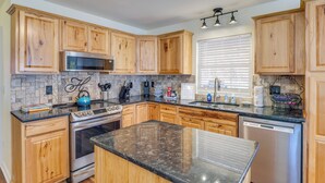 A kitchen with wooden cabinets, a stove, a dishwasher, and a granite countertop. - Lyles Peaceful Creekside Home: Hot Tub & Fire Pit (Lyles)