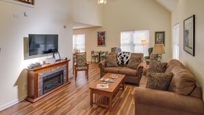 A spacious living room with a fireplace, a television, a sofa, and a coffee table. - Lyles Peaceful Creekside Home: Hot Tub & Fire Pit (Lyles)