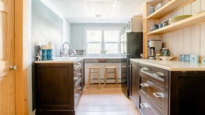 Une cuisine compacte dotée d’un îlot central, de meubles en bois et d’une fenêtre qui laisse entrer la lumière naturelle.