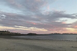 Ein Strand mit ruhiger See und einem Sonnenuntergangshimmel.