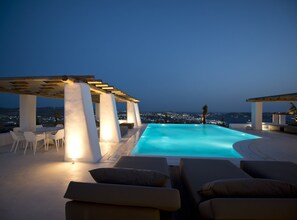 A rooftop infinity pool with a view of a city at dusk. - ISholidays Mykonos Villa Opal (Tourlos)