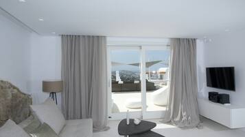 A modern hotel room with a large sliding glass door leading to a balcony with a city view.