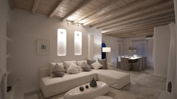 A modern living room with a white sofa, ottoman, and a dining area with a table and chairs.