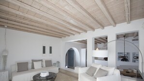 Un salon moderne avec un plafond en bois, des canapés blancs, une table basse ronde et un design minimaliste.