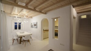 A modern interior with a dining area, kitchen, and staircase. - ISholidays Mykonos villa Pearl (Ornos)