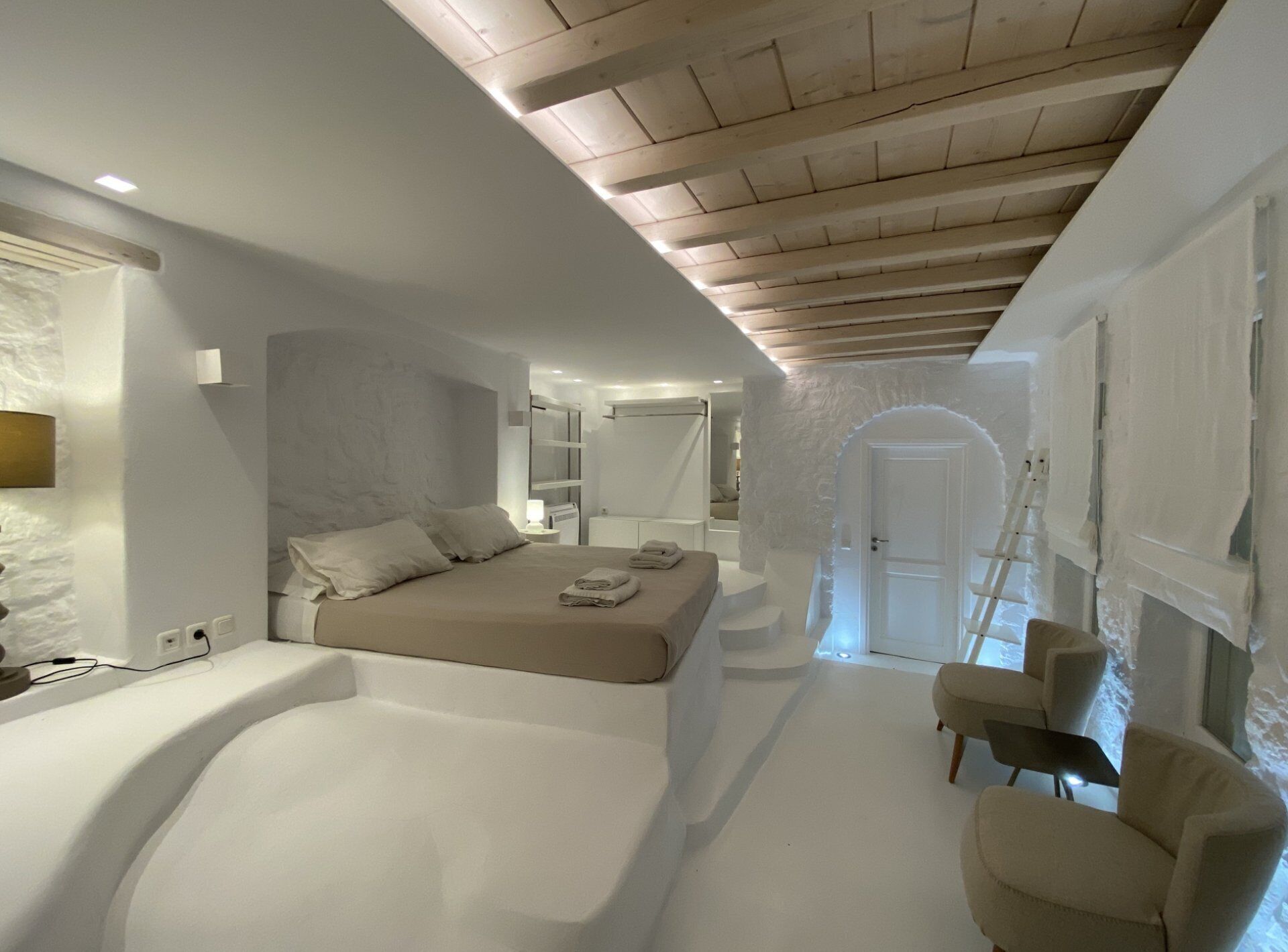 Una camera da letto moderna con un letto grande, un divano piccolo e una cabina armadio.