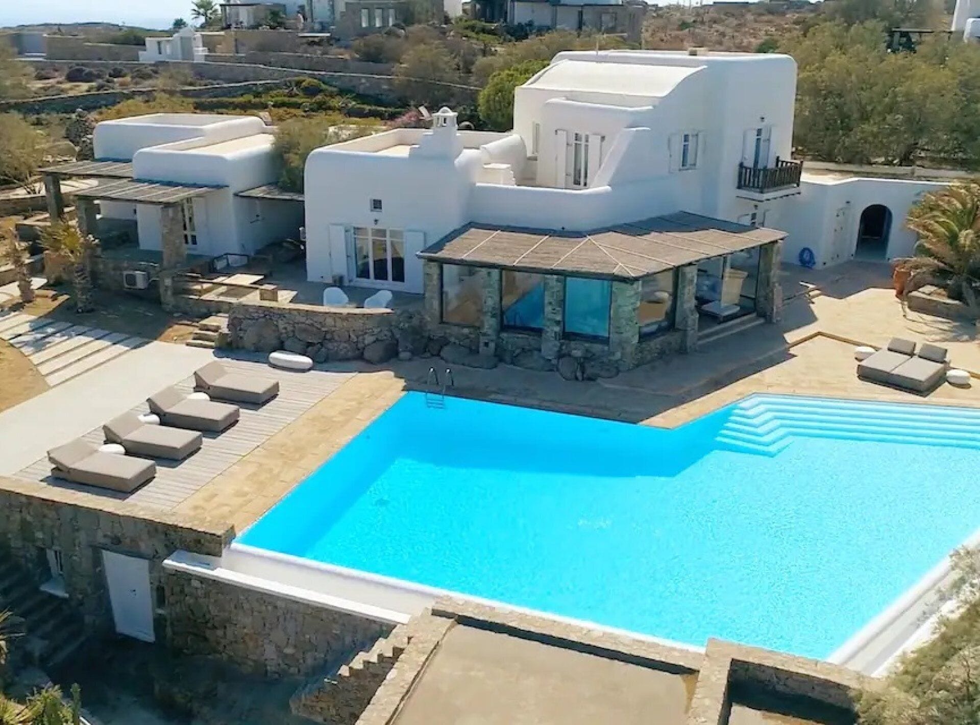 Una villa moderna con piscina, muri in pietra e area salotto esterna.