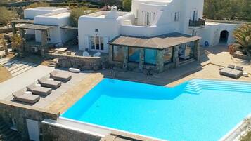 Una villa moderna con piscina, muri in pietra e area salotto esterna.