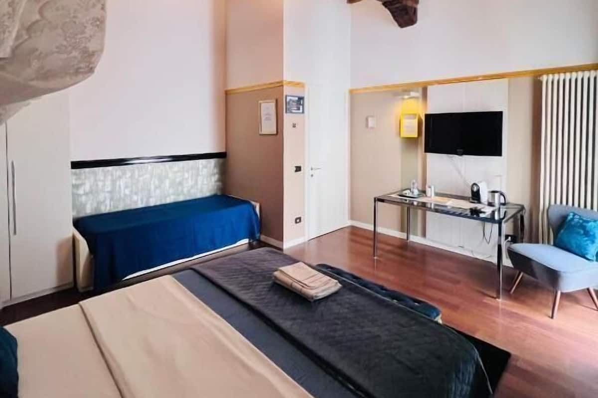 A bedroom with a bed, a desk, and a chair.