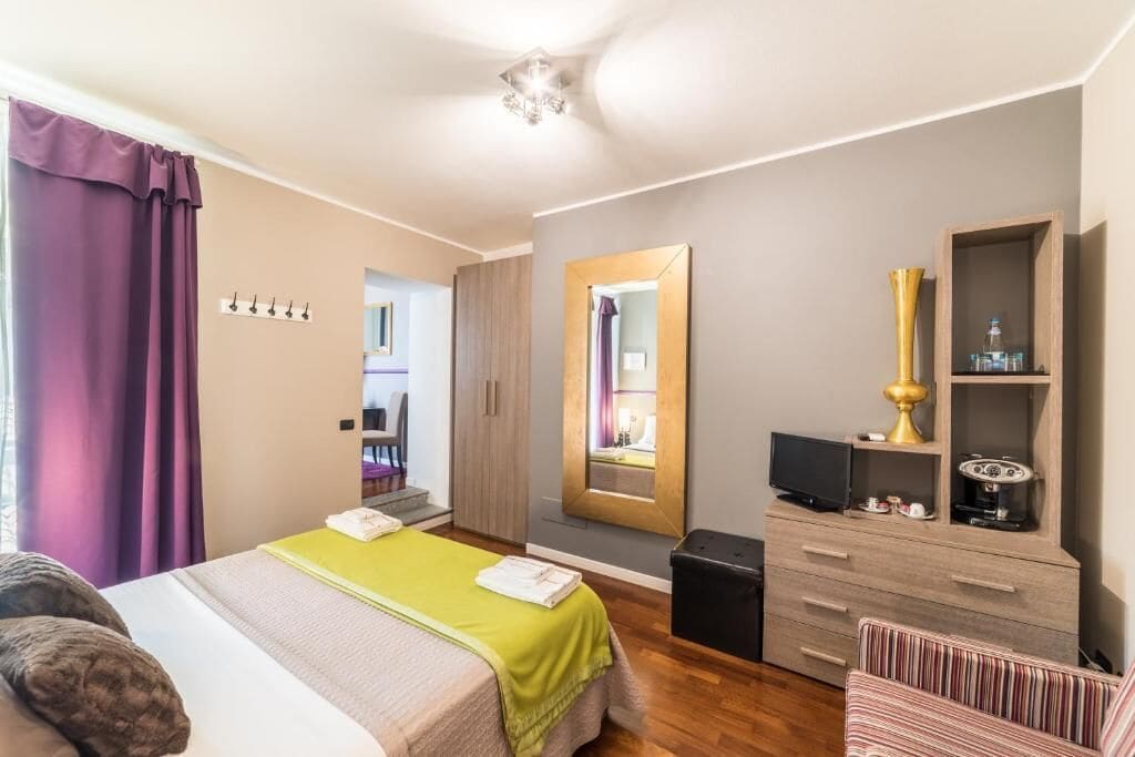 Une chambre d’hôtel avec un lit, une commode, un miroir et un téléviseur.