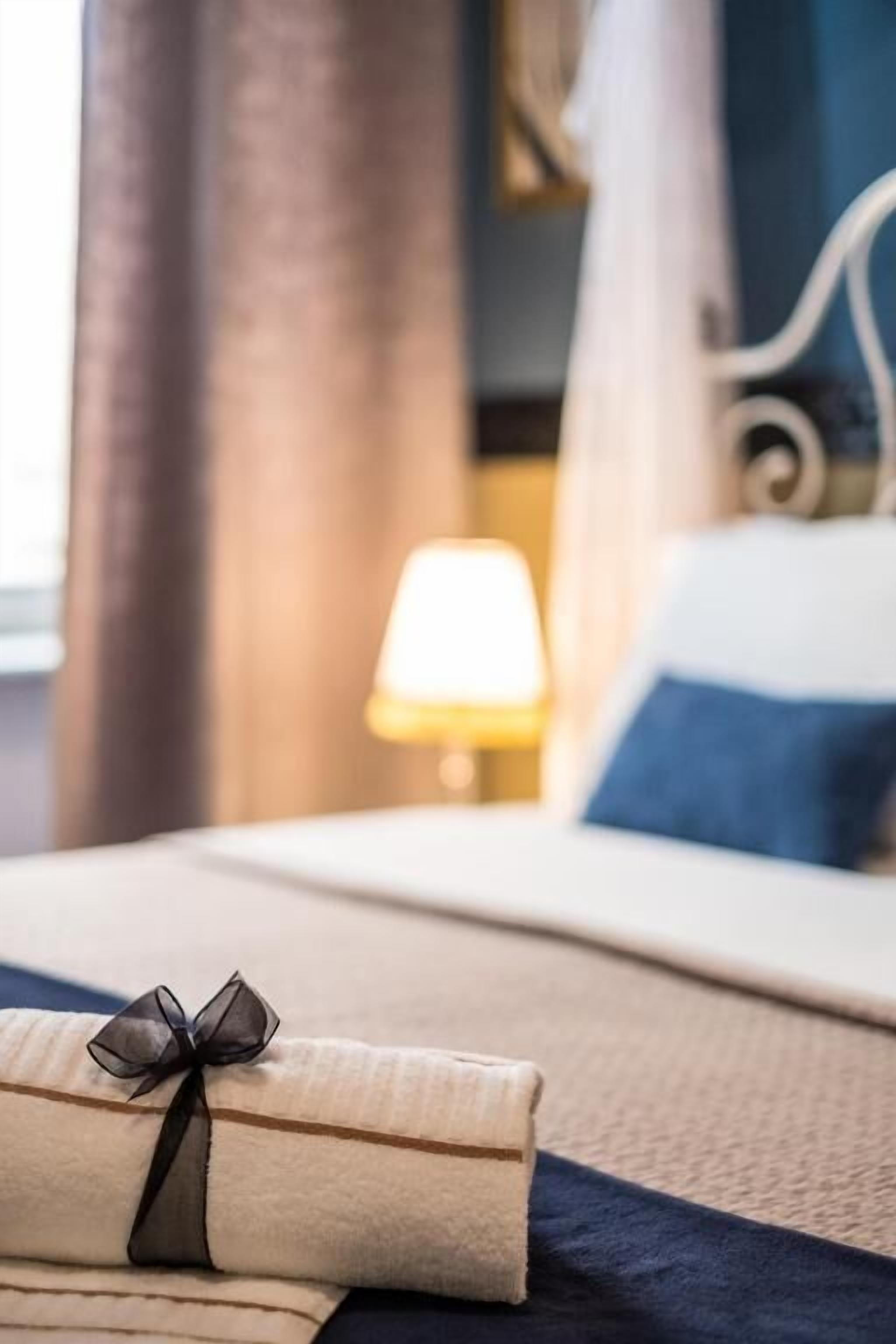 Un lit bien fait, avec une serviette pliée et une boîte cadeau posée dessus.