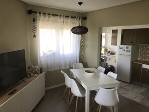 A compact kitchen with a dining area, a TV, and a refrigerator.