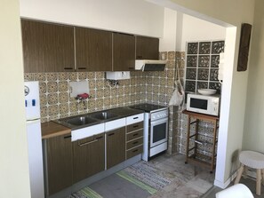 A compact kitchen with wooden cabinets, a built-in oven, a microwave, and a sink.