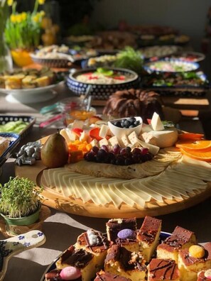 Een buffet met diverse soorten eten, waaronder fruit, kazen en desserts.