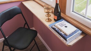 A room corner with a window seat, a chair, a wine bottle, and books. - Willa Dąbrówka (Karpacz)