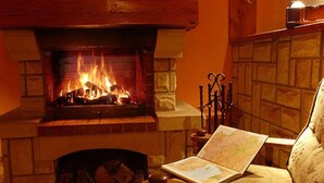 A fireplace with a fire, a book on a table, and a patterned rug. - Willa Dąbrówka (Karpacz)