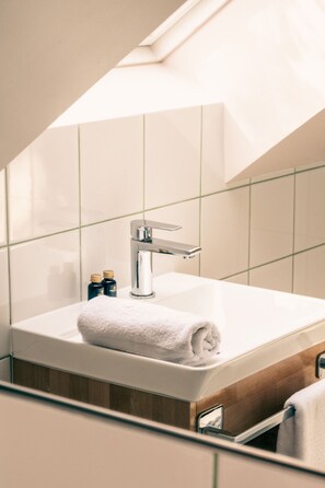 Een moderne badkamer met een wit wastafel, een chromen kraan en een handdoek op het aanrecht.