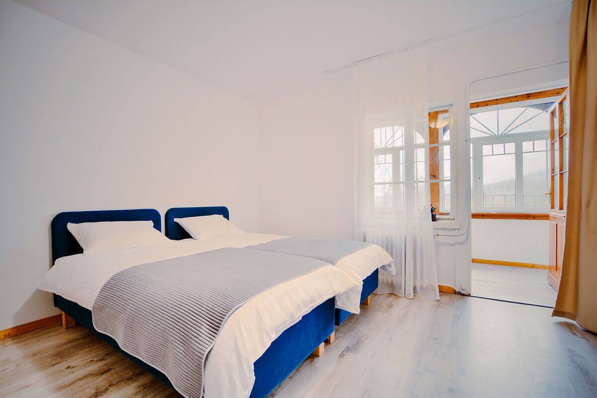 A bedroom with a bed, a window, and a door.