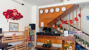 Vestíbulo de hotel con una recepción, relojes y una escalera.