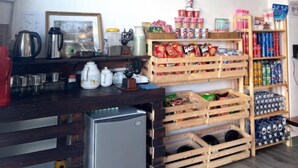 Una cocina con cajas de madera, un refrigerador y estantes llenos de diversos alimentos.