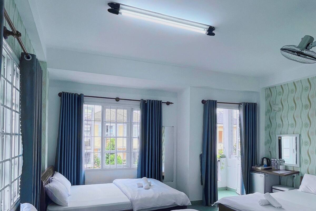 A hotel room with two beds, a desk with a mirror, and a window with curtains.