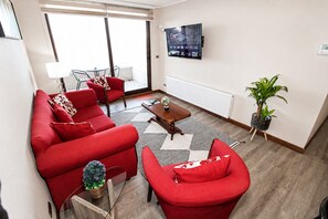 Ein modernes Wohnzimmer mit einer roten Sofagarnitur, einem Couchtisch und einem an der Wand befestigten Fernseher.