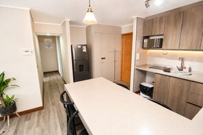 A modern kitchen with a central island, a refrigerator, a microwave, and a sink.