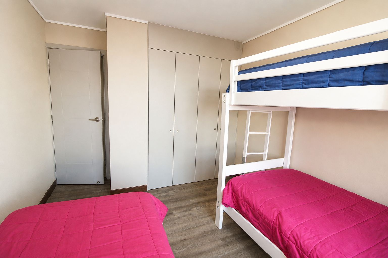 A room with two bunk beds, a wardrobe, and a door.