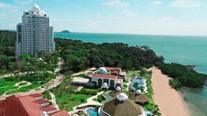 A resort with a beach, a large hotel, and a pool area.