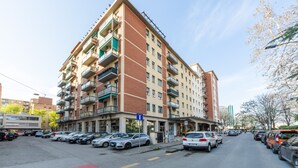 A multi-story apartment building with balconies, parking in front, and a clear sky. - HouSmart Cimabue 1 (Bologna)
