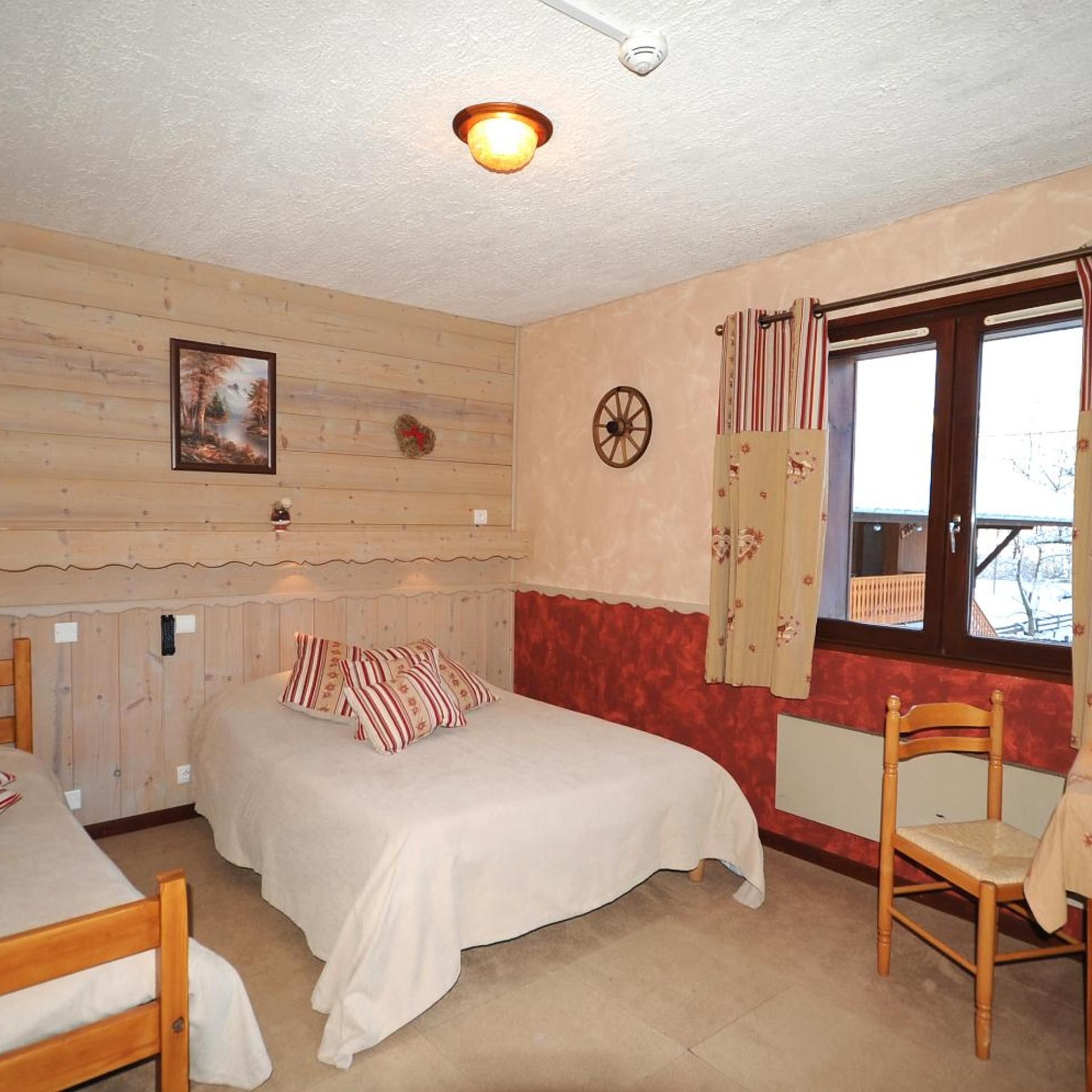 Ein Zimmer mit einem Bett, einem Sessel, einem Fenster mit Vorhängen, einer Wanduhr und einem Gemälde.