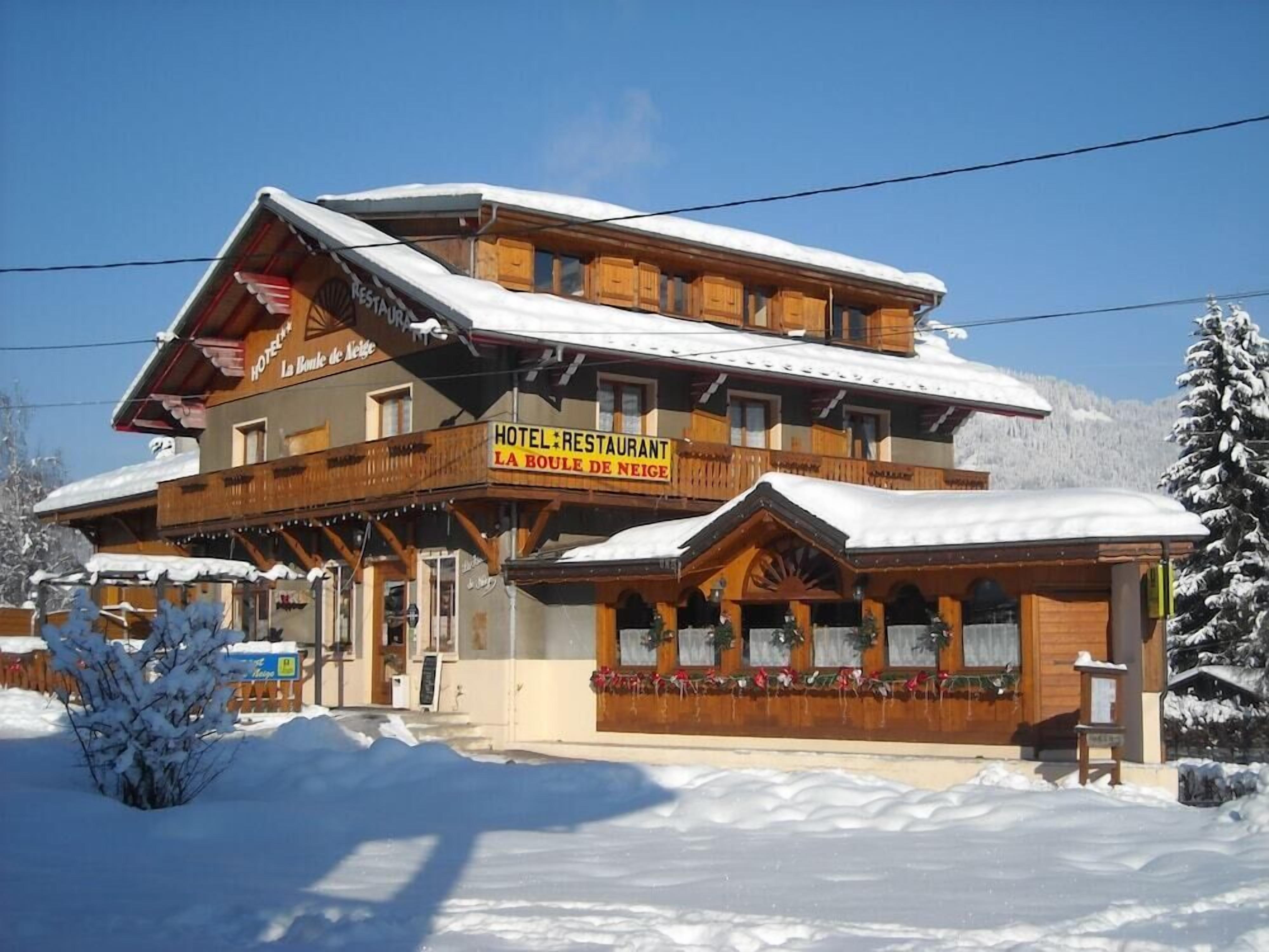 Un edificio de madera de dos pisos con un letrero que dice 'HOTEL RESTAURANT LA BOULE DE NEIGE'.