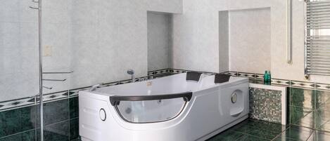 Un baño moderno con una bañera independiente, cabina de ducha con paredes de vidrio y suelo de baldosas.