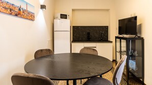 A compact kitchen with a round dining table, chairs, a refrigerator, a microwave, a black countertop, and a glass cabinet with wine glasses. - Afrodite Apartment With Jacuzzi by Wonderful Italy (Bologna)