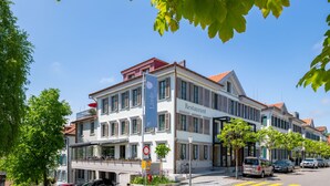 Een meerlaags gebouw met een restaurant op de begane grond, met een balkon en een helderblauwe lucht op de achtergrond.