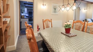 A dining area with a wooden table, chairs, and a chandelier. There is a kitchen visible in the background. - Bottle Tops (Windermere)